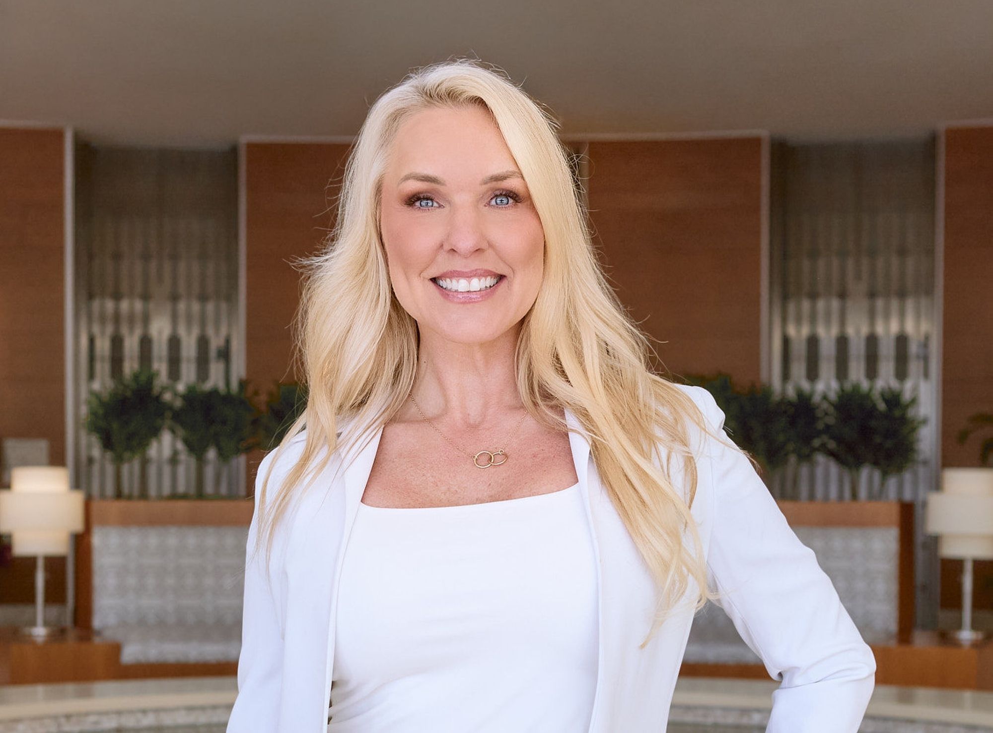 Dr. Karen Stewart in a white outfit standing in front of a wooden panel